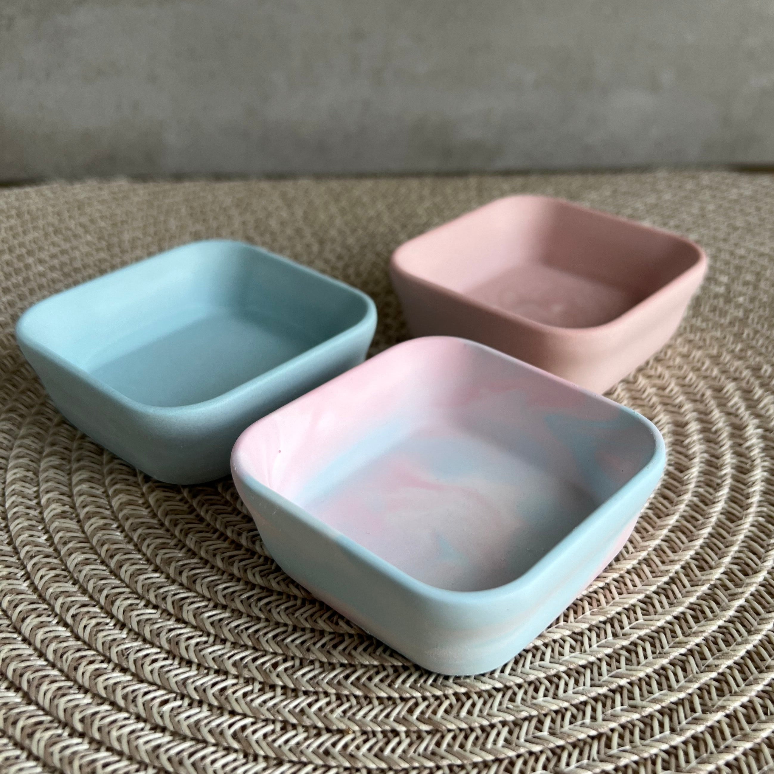 Drei kleine viereckige Schalen, in blau, rosa und blau-rosa marmoriert.