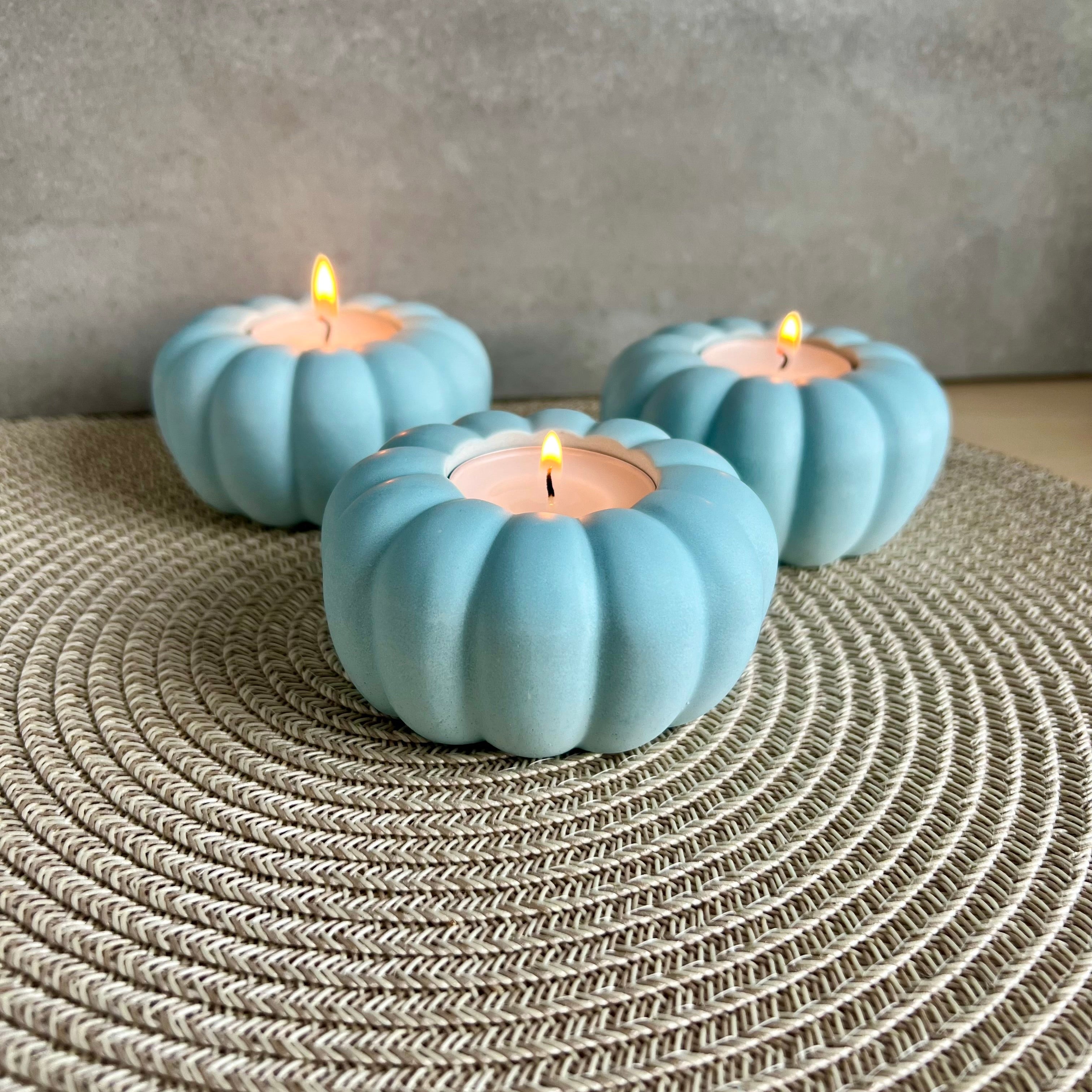 Ein Teelicht-Halter in blau, die Form erinnert an eine Blume oder einen Kürbis. 