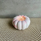 Ein Teelicht-Halter in rosa marmoriert, die Form erinnert an eine Blume oder einen Kürbis. 