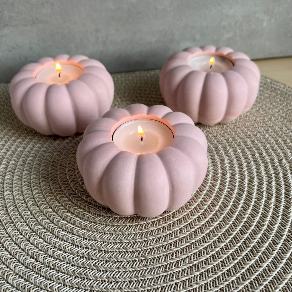 Drei Teelicht-Halter in rosa, die Form erinnert an eine Blume oder einen Kürbis. 
