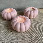 Drei Teelicht-Halter in rosa, die Form erinnert an eine Blume oder einen Kürbis. 