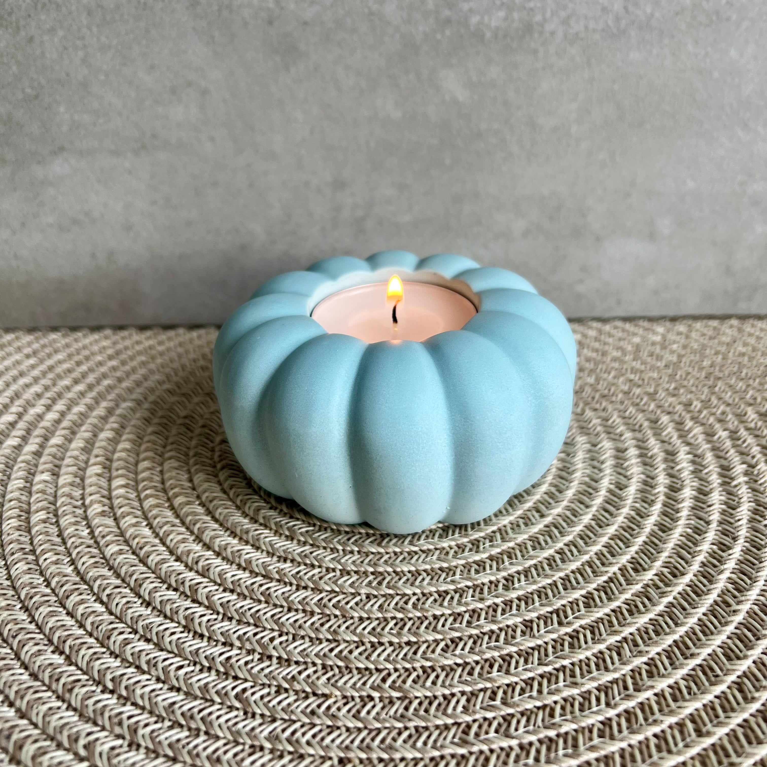 Ein Teelicht-Halter in blaut, die Form erinnert an eine Blume oder einen Kürbis. 