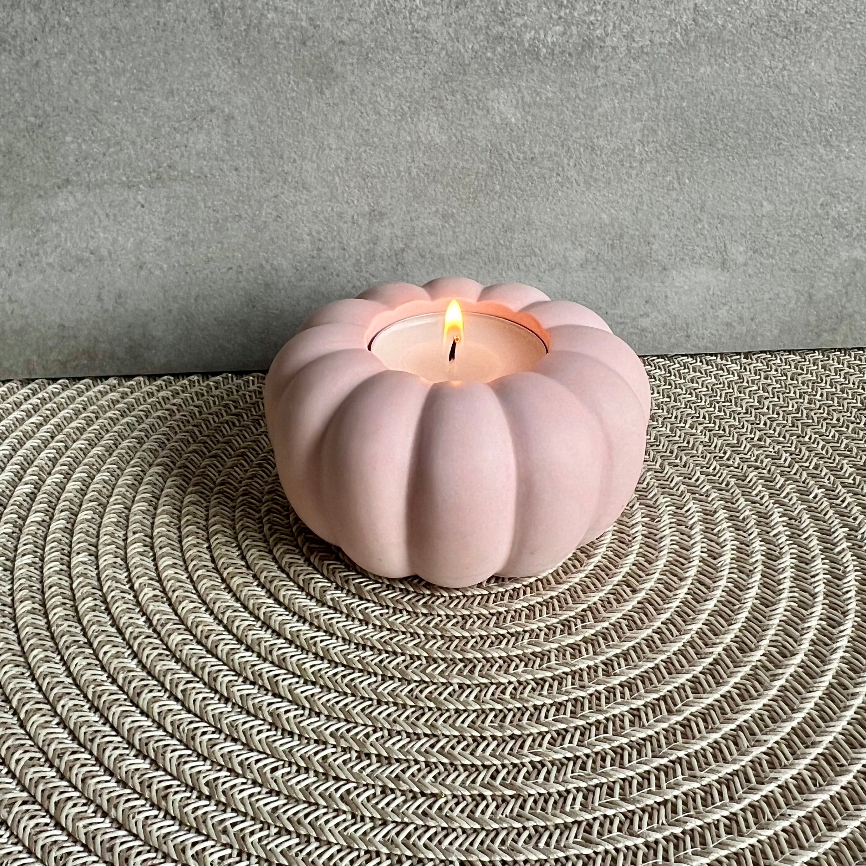 Ein Teelicht-Halter in rosa , die Form erinnert an eine Blume oder einen Kürbis. 