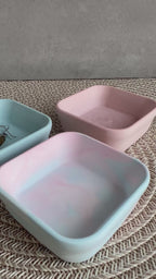 Drei viereckige Schmck-Schalen (blau, rosa und im Vordergrund rosa-blau marmoriert. In die vordere Schale wird eine Kette gelegt. 