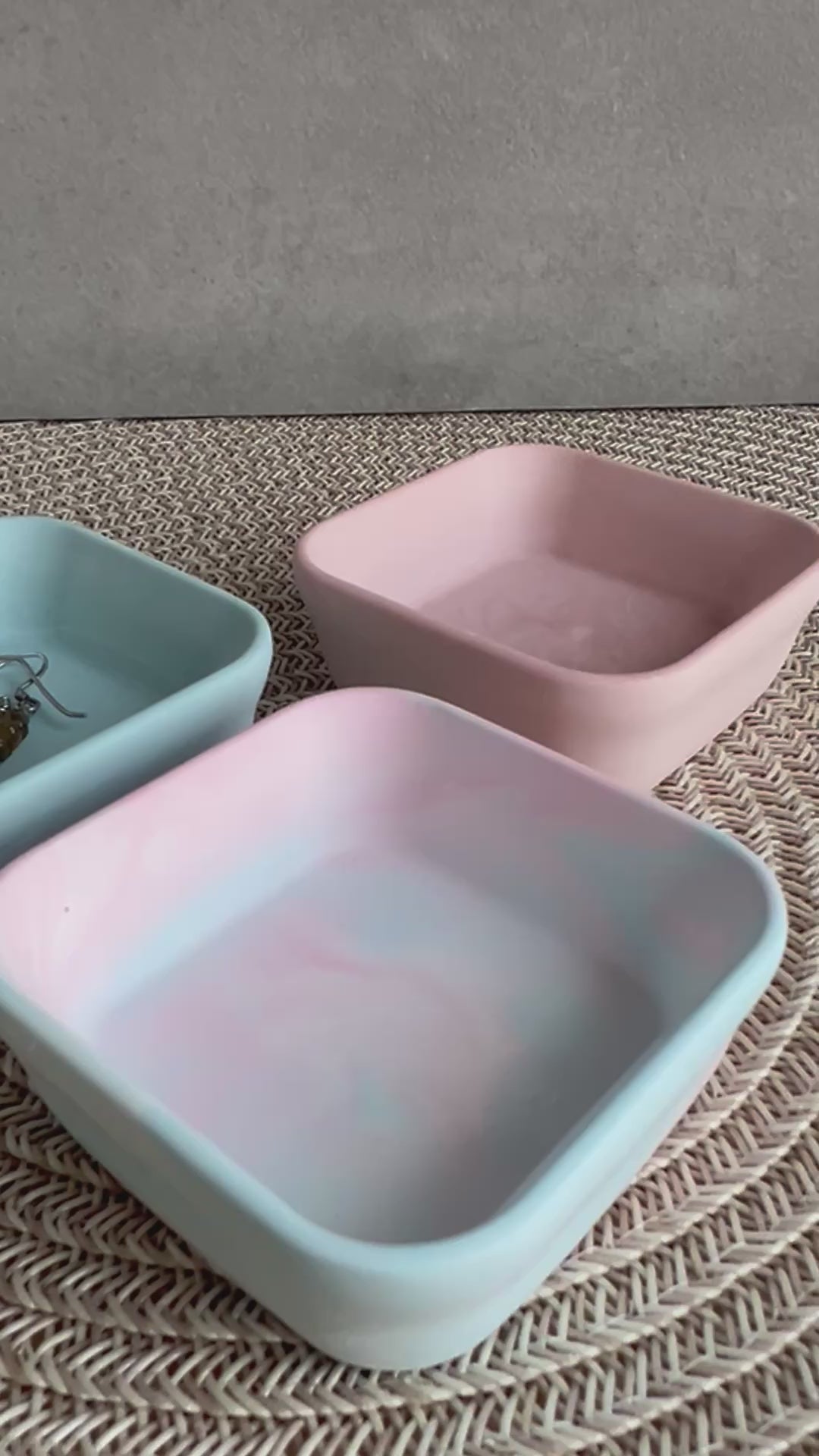 Drei viereckige Schmck-Schalen (blau, rosa und im Vordergrund rosa-blau marmoriert. In die vordere Schale wird eine Kette gelegt. 